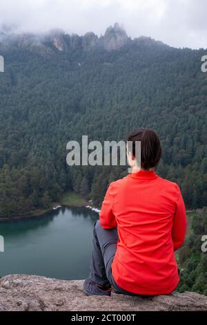 Die mexikanische Wanderin sitzt am Rand der Klippe und bewundert die Aussicht Stockfoto