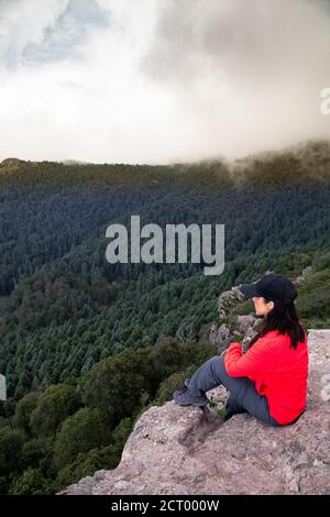 Die mexikanische Wanderin sitzt am Rand der Klippe und bewundert die Aussicht Stockfoto