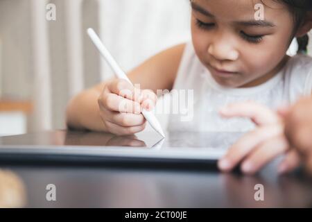 Kleines Mädchen mit Tablet und Stift lernen Zeichnung online. Fernschulungskonzept. Stockfoto