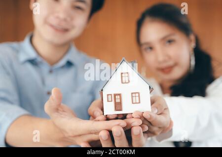 Junges Paar zeigt Haus Modell. Immobilien, Kauf oder Verkauf oder Umzug oder Vermietung von Immobilien. Hypothek- und Geschäftskonzept. Stockfoto