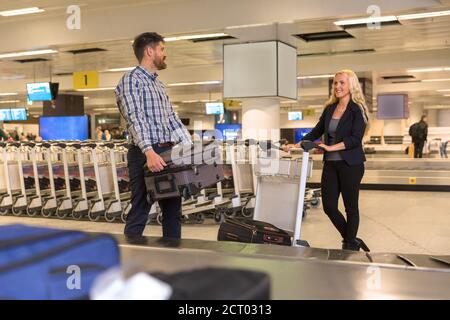 Positive männliche und weibliche Reisende mit Koffern, die im Flughafen stehen Terminal Stockfoto