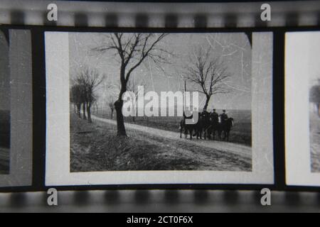 Feine Schwarz-Weiß-Fotografie aus den 1970er Jahren von fünf Männern auf Pferden, die einen Landweg hinuntertraben. Stockfoto