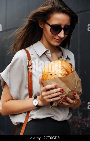 Hungrige Geschäftsfrau auf der Straße mit knusprigem Brot Ihre Hände Stockfoto