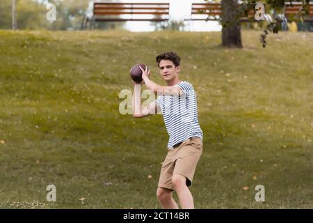 Teenager Junge spielt american Football im grünen Park Stockfoto