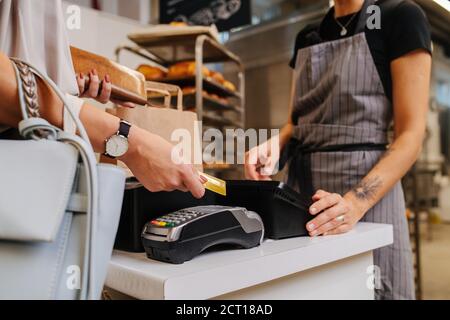 Bezahlen mit ihrer Kreditkarte in einem Bäckereigeschäft, machen einen Kauf Stockfoto
