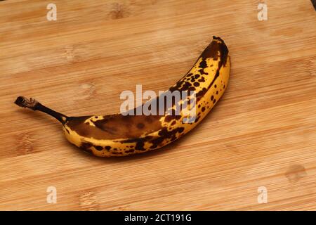 Alte Banane auf Holzbrett. Überreife gelbe Bananen auf altem Holzbrett. Stockfoto