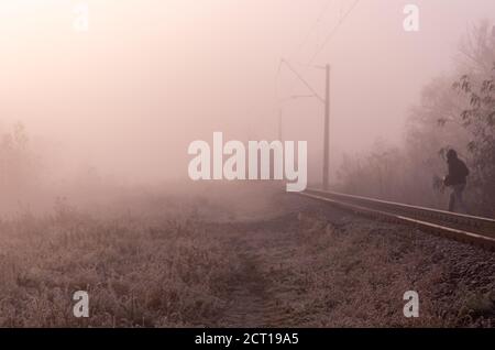 Ein Mann überquert die Schienen. Überqueren Sie die Straße an der falschen Stelle. Sperrgebiet. Stockfoto