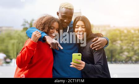 Multi ethnische Freunde im Freien suchen Smartphone-Bildschirm. Diverse Gruppe Menschen Afro american Asian verbringen Zeit zusammen multirassischen männlichen weiblichen Studen Stockfoto