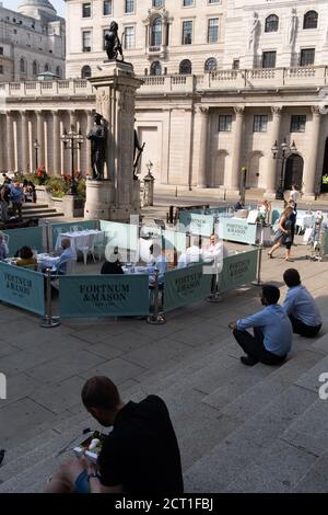 Diners und Trinker sitzen auf Straßensperren, wo Fortnum & Mason während der Coronavirus-Pandemie am 9. September 2020 in London, England, ein Restaurant und eine Bar im Freien vor der Royal Exchange at Bank in der City of London eingerichtet haben. Stockfoto