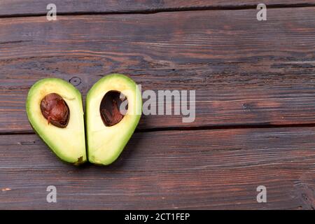 Zwei Scheiben Avocado auf dem Holztisch. Eine Schicht mit Kern. Gesunde Ernährung und Diät-Konzept. Stockfoto