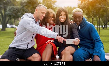 Multi ethnische Freunde im Freien suchen Smartphone-Bildschirm. Diverse Gruppe Menschen Afro american asiatisch kaukasisch verbringen Zeit zusammen multirassischen männlichen Fem Stockfoto