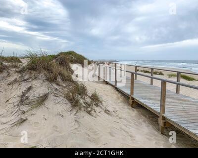 Holzboardwalk in der Nähe der Sanddünen in Costa Nova, Portugal mit dem Meer im Hintergrund Stockfoto