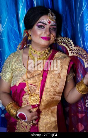 Porträt eines niedlichen indischen Modell in Braut-Look mit Schwerer Goldschmuck und roter Sari Stockfoto