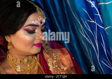 Porträt eines niedlichen indischen Modell in Braut-Look mit Schwerer Goldschmuck und roter Sari Stockfoto