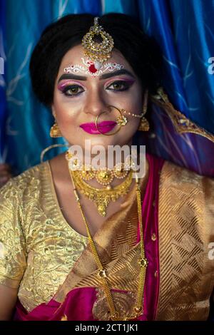 Porträt eines niedlichen indischen Modell in Braut-Look mit Schwerer Goldschmuck und roter Sari Stockfoto