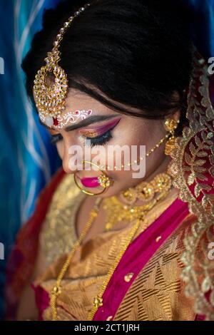 Porträt eines niedlichen indischen Modell in Braut-Look mit Schwerer Goldschmuck und roter Sari Stockfoto