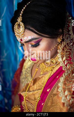 Porträt eines niedlichen indischen Modell in Braut-Look mit Schwerer Goldschmuck und roter Sari Stockfoto