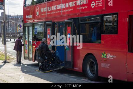 Behinderter Mann im Rollstuhl betritt einen öffentlichen Londoner Bus über eine Rampe während der Coronavirus ( covid-19 ) Pandemie im Jahr 2020. Stockfoto