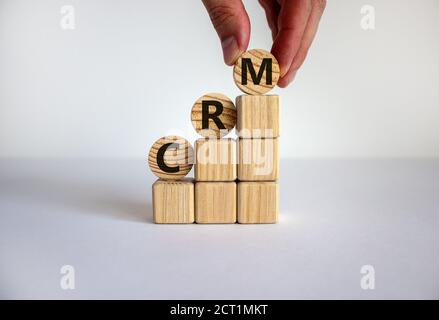 Konzeptwörter „CRM, Customer Relationship Management“ auf Holzwürfeln und Kreisen auf einem schönen weißen Hintergrund. Männliche Hand. Geschäftskonzept. Kopie en Stockfoto