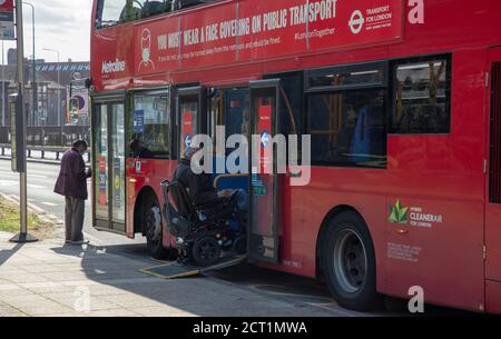 Behinderter Mann im Rollstuhl betritt einen öffentlichen Londoner Bus über eine Rampe während der Coronavirus ( covid-19 ) Pandemie im Jahr 2020. Stockfoto