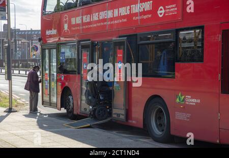 Behinderter Mann im Rollstuhl betritt einen öffentlichen Londoner Bus über eine Rampe während der Coronavirus ( covid-19 ) Pandemie im Jahr 2020. Stockfoto