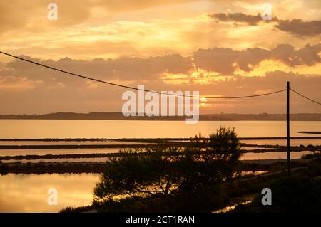 Sonnenaufgang mit goldenen Wolken und Sonnenstrahlen in Estany Pudent salinas im Naturpark Ses Salines (Formentera, Balearen, Mittelmeer, Spanien) Stockfoto