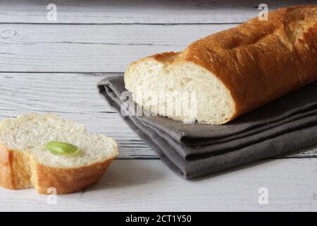 Französisches frisches weiches Brot Baguette auf Serviette und Holzhintergrund. Mehrere geschnittene Stücke liegen nebeneinander. Stockfoto