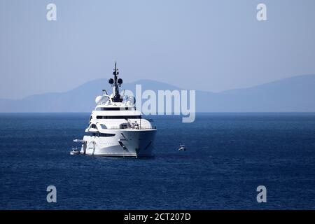 Luxusyacht mit Hubschrauberlandeplatz und Hubschraubersegeln im Meer, Vorderansicht. Weißes futuristisches Boot auf Berg Insel Hintergrund Stockfoto