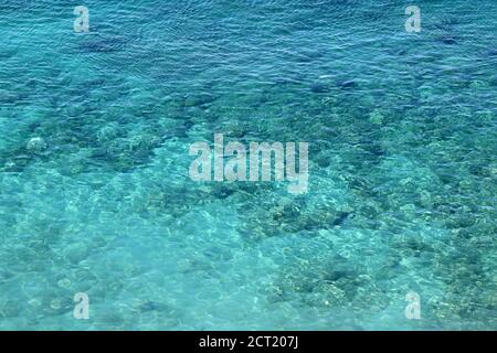 Azure Wasser Textur, transparente Meeresoberfläche mit einem felsigen Boden. Luftaufnahme, natürlicher blauer Hintergrund Stockfoto
