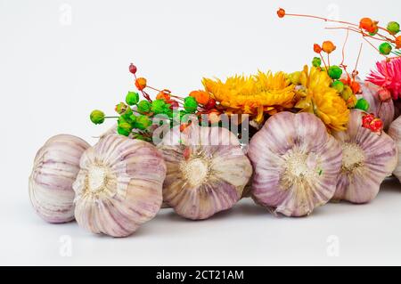 Ein mit Blumen geschmücktes Zopf aus Knoblauch vor hellem Hintergrund, aus der Nähe fotografiert Stockfoto