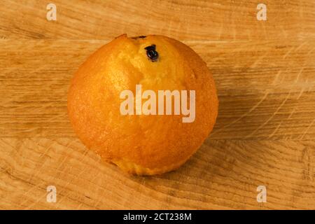 Ein hellbrauner Cupcake liegt auf einem Holzbrett Stockfoto