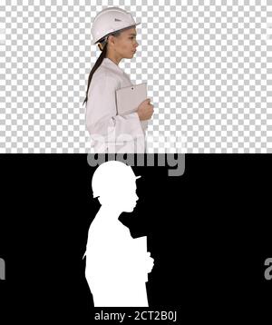 Attraktive hispanische Frau in weißem Labormantel und weißer Sicherheit har Stockfoto