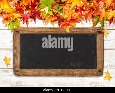 Herbstblätter und Kreidetafel auf hellem Holzhintergrund Stockfoto