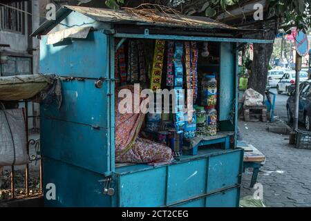 Kolkata, Indien - 1. Februar 2020: Ein nicht identifizierter Händler in sitzt in ihrem kleinen blau-türkisfarbenen Stallladen am Straßenrand Stockfoto