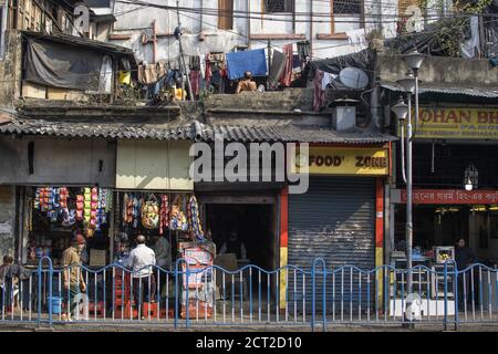 Kolkata, Indien - 1. Februar 2020: Nicht identifizierte Männer kaufen und verkaufen Artikel an einem kleinen Verkaufsstand und hängen Wäsche trocknen auf dem Dach Stockfoto