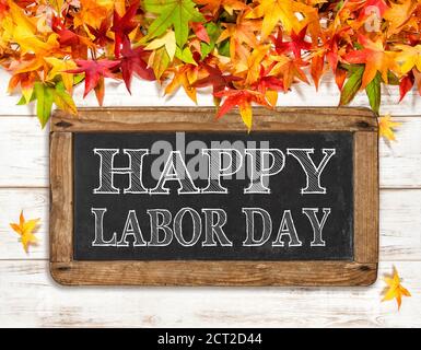 Alles gute zum Labour Day. Herbstblätter und Kreidetafel auf hellem Holzhintergrund Stockfoto