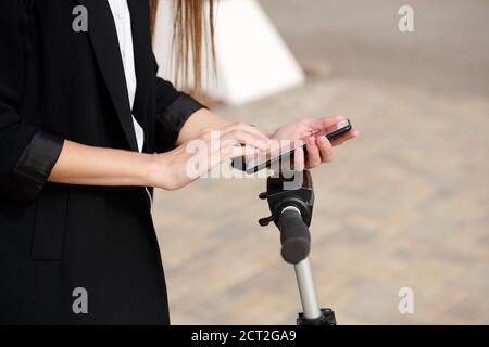 Hände der jungen Frau in schwarz Cardigan Scrolling im Smartphone Über dem Bedienfeld Stockfoto