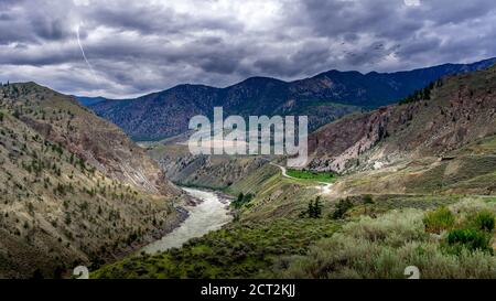 Blitzschlag und eine Vogelschar bei schlechtem Wetter über dem Fraser Canyon und Highway 99 in der Nähe von Lillooet in British Columbia, Kanada Stockfoto