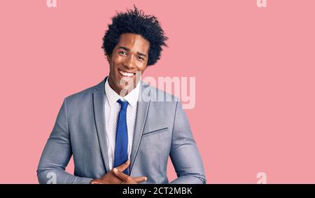 Schöner afroamerikanischer Mann mit Afro-Haar trägt Business-Jacke lächeln und lachen hart aus laut, weil lustig verrückt Witz mit Händen am Körper. Stockfoto