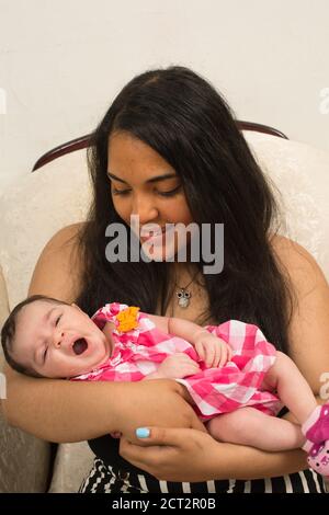 3 Wochen altes neugeborenes Baby Mädchen mit stillenden Blister auf der Lippe, gehalten von Teenager ältere Schwester, Alter 14, Reflex Gähnen Stockfoto