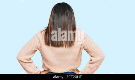 Junge latein Mädchen trägt Wolle Winter Pullover stehen rückwärts suchen Mit den Armen am Körper Stockfoto