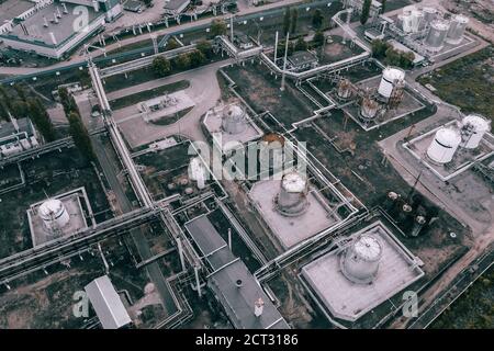 Dunkle industrielle Landschaft Hintergrund von oben. Petrochemische Fabrik mit Rohrleitungen und Stahltanks, Luftaufnahme. Stockfoto