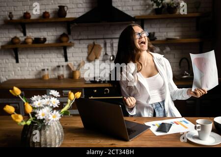 Glückliche Geschäftsfrau, die von zu Hause aus arbeitet. Schöne Dame, die mit Dokumenten in der Küche arbeitet Stockfoto