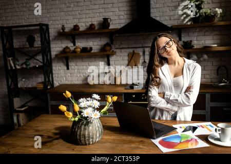 Glückliche Geschäftsfrau, die von zu Hause aus arbeitet. Schöne Dame, die mit Dokumenten in der Küche arbeitet Stockfoto