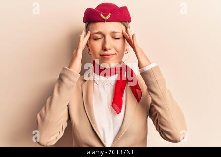 Junge schöne blonde Mädchen trägt Stewardess Uniform leiden unter Kopfschmerzen verzweifelt und gestresst, weil Schmerzen und Migräne. Hände auf dem Kopf. Stockfoto