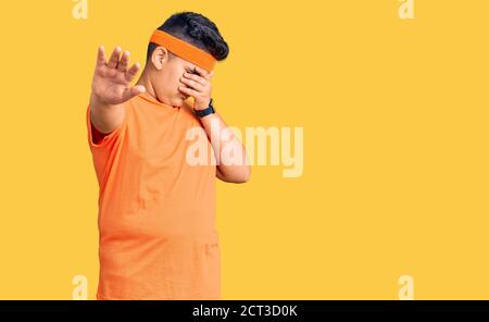 Kleiner Junge Kind trägt Sportkleidung, die Augen mit Händen und tun Stop-Geste mit traurig und Angst Ausdruck. Peinlich und negativ Konzept. Stockfoto