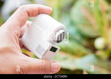 Pranburi, Thailand - 15. September 2020: Ein weißer Xiaomi Xiaoda automatischer Wassersparer auf der Hand mit Baumblättern Hintergrund Stockfoto