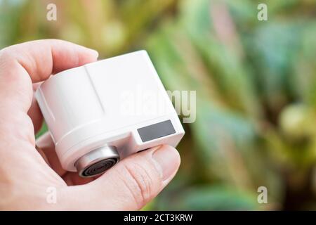 Pranburi, Thailand - 15. September 2020: Ein weißer Xiaomi Xiaoda automatischer Wassersparer auf der Hand mit Baumblättern Hintergrund Stockfoto