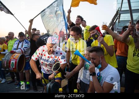 Ein Mann in einem T-Shirt mit Polka-Punkt-T-Shirt hat eine Sirene gekrümmelt, während die Fans während der Feier die Flaggen der slowenischen Radfahrer Tadej Pogacar und Primoz Roglic schwingen. Als der slowenische Tadej Pogacar die diesjährige Tour de France gewann, versammelten sich die Menschen in Komenda, seiner Heimatstadt, Um die Preisverleihung im Fernsehen zu feiern und zu beobachten. Stockfoto