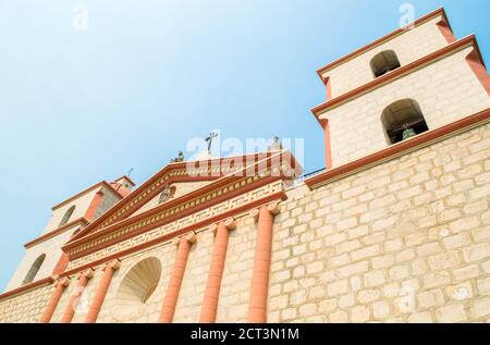 Neoklassizistische Glockentürme und Portikus an der historischen Santa Barbara Mission in Kalifornien unter trüben Sonnenschein von unten betrachtet mit Speicherplatz kopieren Stockfoto